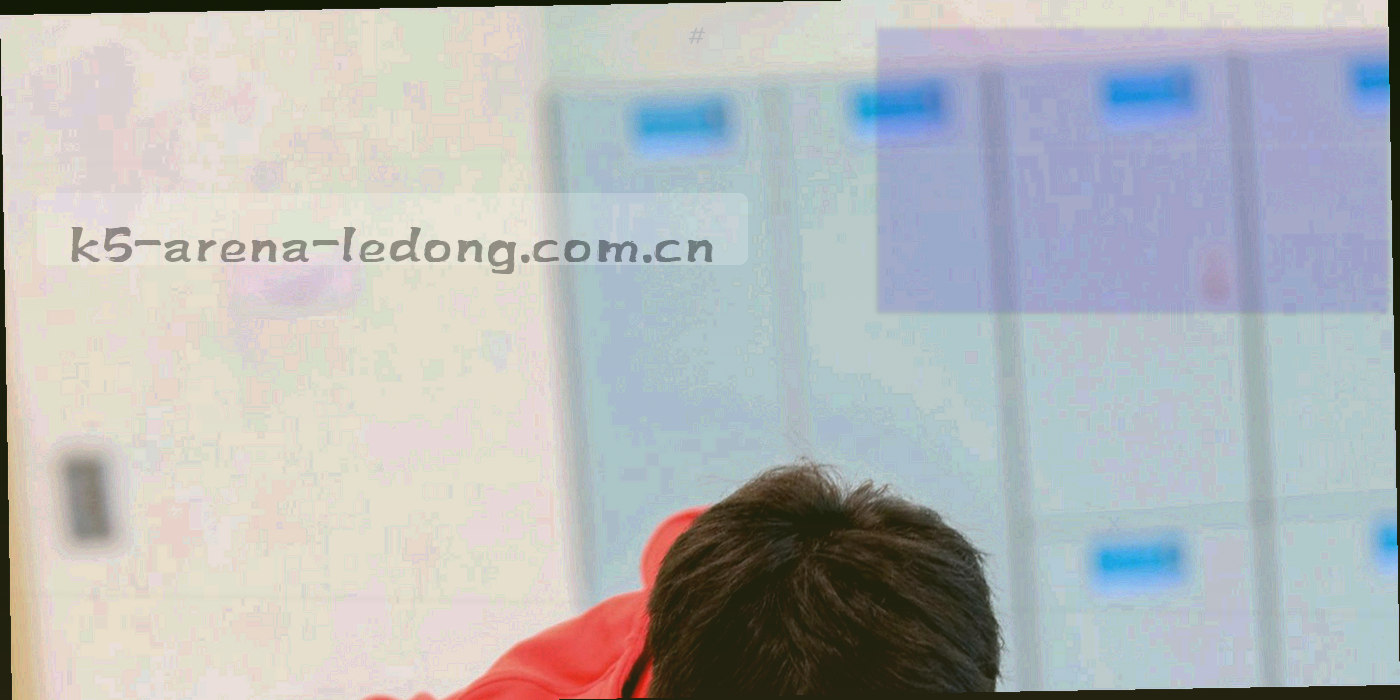 夜间球场通道与灯光明暗交错，工作人员虚化背影走向看台